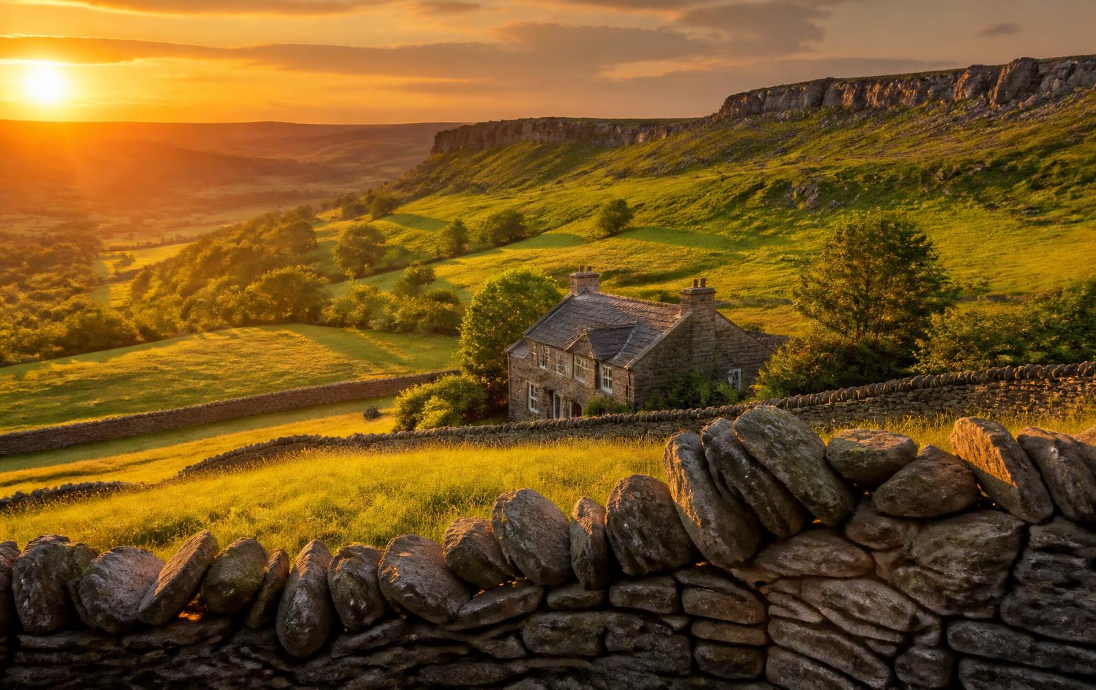Peak District valley at sunset with a stone holiday cottage and dry stone walls