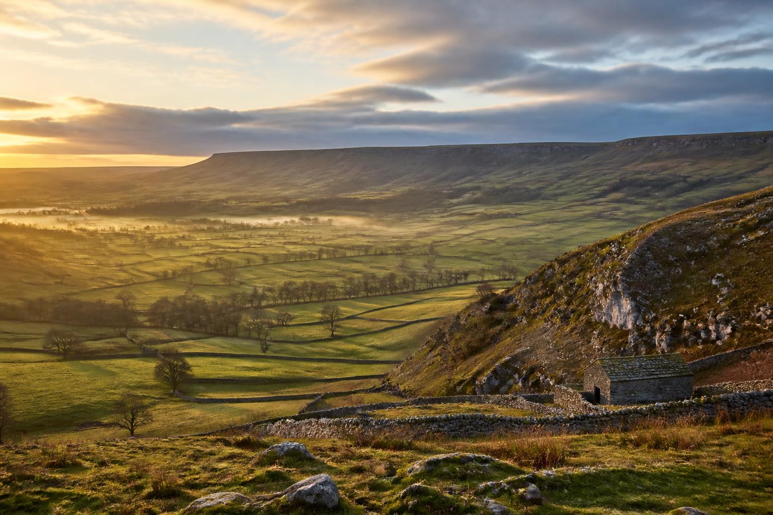 Peak District valley at golden hour with dry stone walls and rolling hills